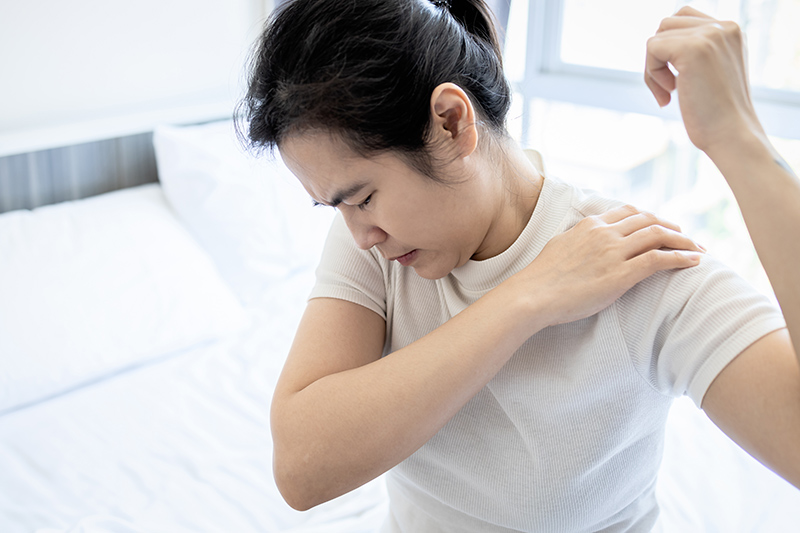 Woman experiencing shoulder pain while raising her arm